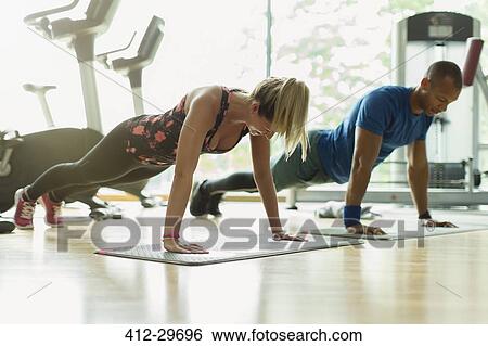 Man and woman doing planks at gym View Large Photo Image Stock Photograph - Man and woman doing planks at gym. Fotosearch