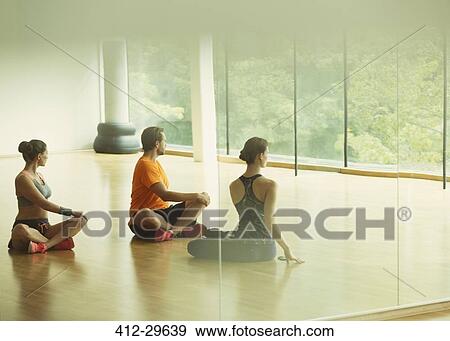 Stock Photo - Man and women doing twisted stretch in gym studio. Fotosearch