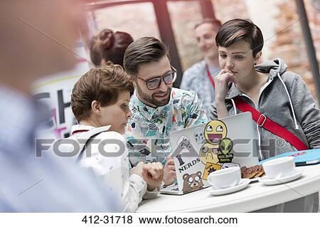 Stock Photo - Man and women using laptop in cafeteria. Fotosearch