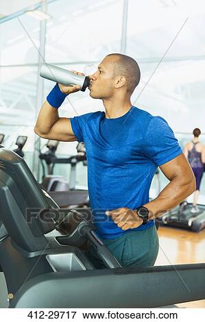 Man drinking water on treadmill at gym View Large Photo Image Stock Photo - Man drinking water on treadmill at gym. Fotosearch