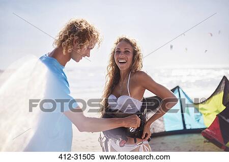 Man fastening kiteboarding safety harness on woman on sunny beach View Large Photo Image Stock Photography - Man fastening kiteboarding safety harness on woman on sunny beach. Fotosearch