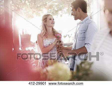 Stock Image - Man giving woman flowers in flower shop. Fotosearch