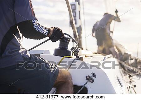 Stock Photo - Man holding sailing rigging on sailboat. Fotosearch