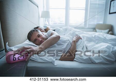 Man in bed turning off morning alarm clock View Large Photo Image Stock Image - Man in bed turning off morning alarm clock. Fotosearch