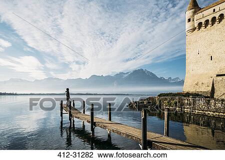 Stock Image - Man on sunny lakeside dock outside Chillon Castle, Switzerland. Fotosearch