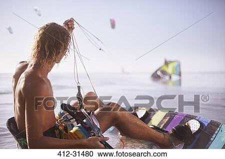 Stock Image - Man ready to kiteboard on beach. Fotosearch