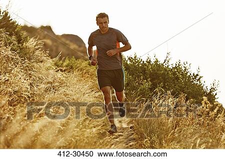 Man running on trail through tall grass View Large Photo Image Stock Image - Man running on trail through tall grass. Fotosearch