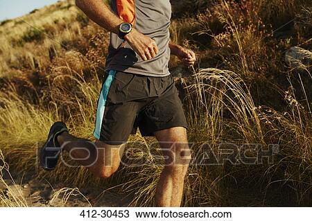 Man running on trail through tall grass View Large Photo Image Stock Image - Man running on trail through tall grass. Fotosearch