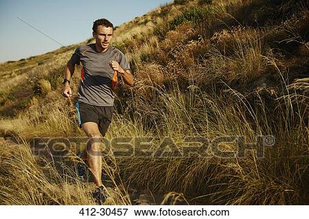 Man running on trail through tall grass View Large Photo Image Stock Photo - Man running on trail through tall grass. Fotosearch