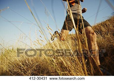 Man running through tall grass on sunny trail View Large Photo Image Stock Image - Man running through tall grass on sunny trail. Fotosearch