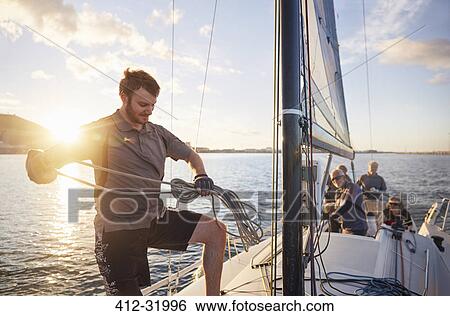 Man sailing looping rigging on sailboat View Large Photo Image Stock Photograph - Man sailing looping rigging on sailboat. Fotosearch