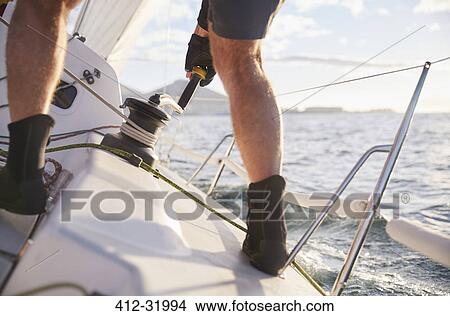 Man sailing turning cable winch on heeling sailboat View Large Photo Image Picture - Man sailing turning cable winch on heeling sailboat. Fotosearch