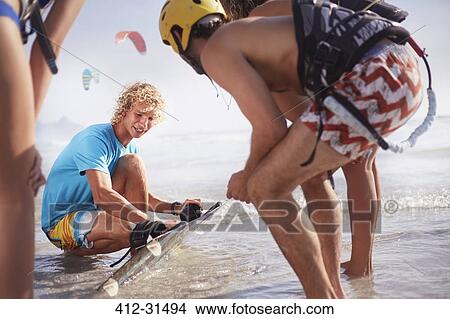 Man teaching friends kiteboarding in ocean surf View Large Photo Image Picture - Man teaching friends kiteboarding in ocean surf. Fotosearch