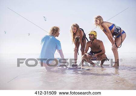 Man teaching friends kiteboarding on sunny beach View Large Photo Image Stock Photo - Man teaching friends kiteboarding on sunny beach. Fotosearch