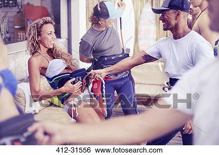 Stock Photograph - Man teaching woman kiteboarding technique at surf shop. Fotosearch