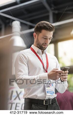 Stock Photo - Man texting with cell phone at technology conference. Fotosearch