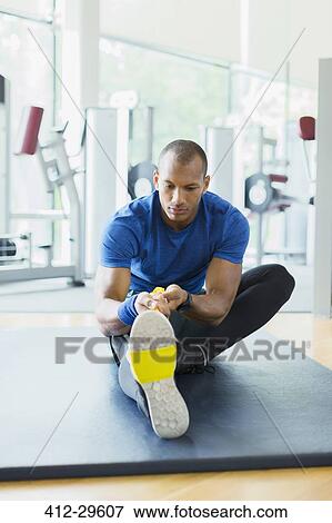 Man using resistance band to stretch leg at gym View Large Photo Image Stock Photo - Man using resistance band to stretch leg at gym. Fotosearch