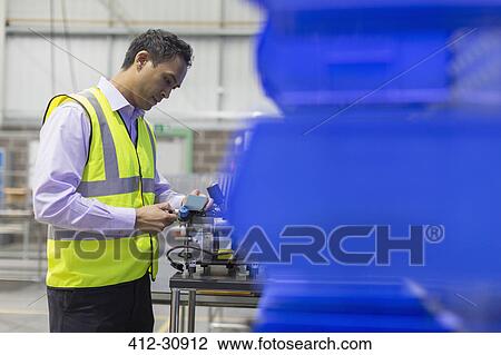 Stock Image - Manager examining part in steel factory. Fotosearch