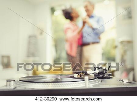 Mature couple dancing in living room behind record player View Large Photo Image Stock Image - Mature couple dancing in living room behind record player. Fotosearch