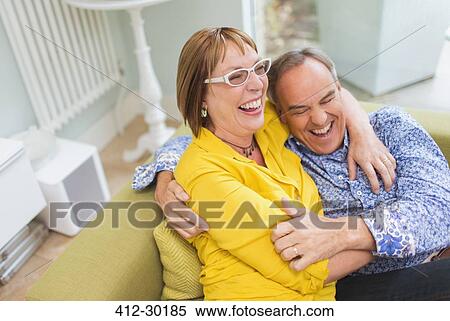 Mature couple laughing and hugging on sofa View Large Photo Image Stock Photography - Mature couple laughing and hugging on sofa. Fotosearch