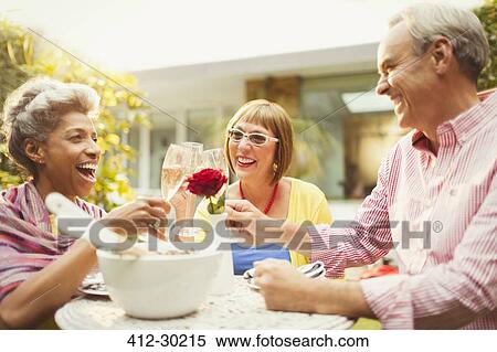 Stock Photography - Mature friends toasting champagne flutes in garden. Fotosearch
