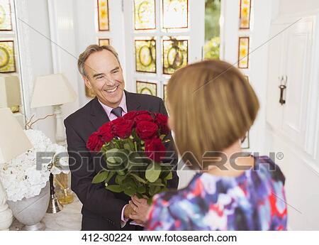 Mature man giving rose bouquet to wife View Large Photo Image Picture - Mature man giving rose bouquet to wife. Fotosearch