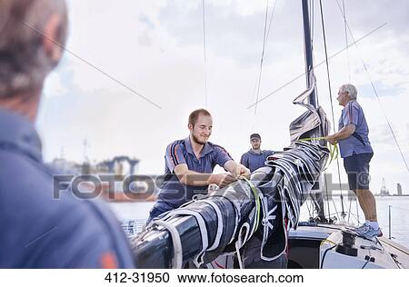 Stock Image - Men preparing sailing equipment. Fotosearch