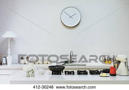 Stock Photo - Modern clock on wall in kitchen. Fotosearch