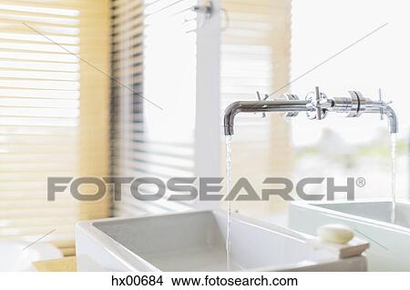 Modern mirror-mounted faucet dripping into bathroom sink View Large Photo Image Picture - Modern mirror-mounted faucet dripping into bathroom sink. Fotosearch