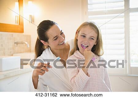 Mother and daughter brushing teeth in bathroom View Large Photo Image Stock Image - Mother and daughter brushing teeth in bathroom. Fotosearch