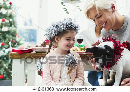 Mother and daughter feeding dog at Christmas dinner View Large Photo Image Stock Photo - Mother and daughter feeding dog at Christmas dinner. Fotosearch