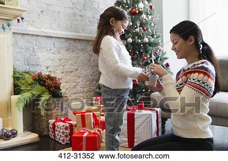 Mother and daughter opening Christmas gift in living room View Large Photo Image Stock Image - Mother and daughter opening Christmas gift in living room. Fotosearch