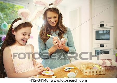 Mother and daughter wearing costume rabbit ears coloring Easter eggs and cookies View Large Photo Image Stock Photograph - Mother and daughter wearing costume rabbit ears coloring Easter eggs and cookies. Fotosearch