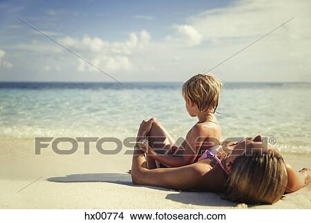 Picture - Mother and son laying and relaxing on tropical beach. Fotosearch
