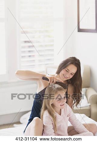 Mother brushing daughters hair on bed View Large Photo Image Picture - Mother brushing daughters hair on bed. Fotosearch