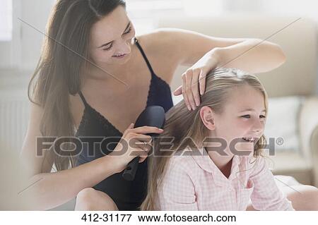 Stock Photo - Mother brushing daughters hair. Fotosearch