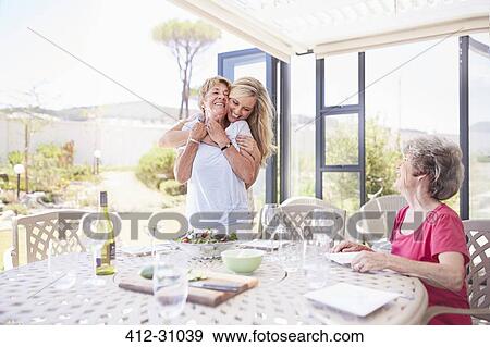 Mother hugging senior mother at patio lunch View Large Photo Image Stock Photo - Mother hugging senior mother at patio lunch. Fotosearch