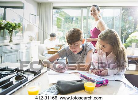 Mother watching brother and sister doing homework at kitchen counter View Large Photo Image Stock Photograph - Mother watching brother and sister doing homework at kitchen counter. Fotosearch