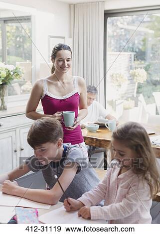Mother with coffee watching daughter and son doing homework View Large Photo Image Stock Photo - Mother with coffee watching daughter and son doing homework. Fotosearch