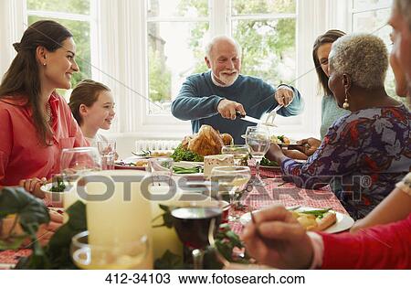 Stock Image - Multi-ethnic family enjoying Christmas dinner table. Fotosearch