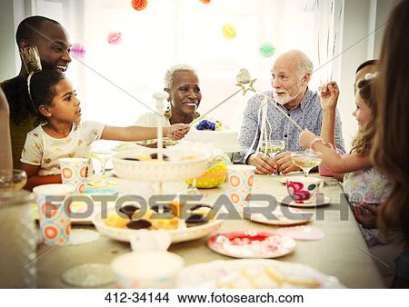 Multi-ethnic multi-generation family celebrating birthday party at table View Large Photo Image Picture - Multi-ethnic multi-generation family celebrating birthday party at table. Fotosearch