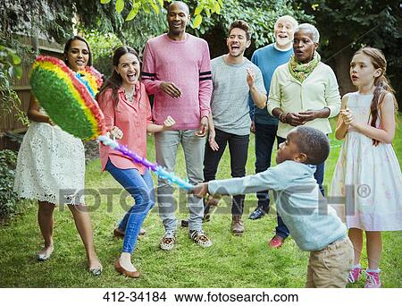 Multi-ethnic multi-generation family cheering boy hitting pinata at birthday party View Large Photo Image Picture - Multi-ethnic multi-generation family cheering boy hitting pinata at birthday party. Fotosearch