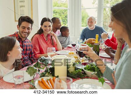 Multi-ethnic multi-generation family enjoying Christmas dinner at table View Large Photo Image Stock Image - Multi-ethnic multi-generation family enjoying Christmas dinner at table. Fotosearch