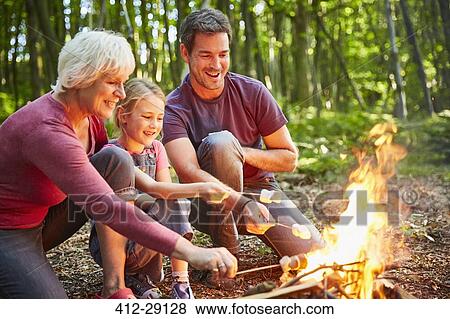 Multi-generation family roasting marshmallows at campfire in forest View Large Photo Image Stock Photo - Multi-generation family roasting marshmallows at campfire in forest. Fotosearch