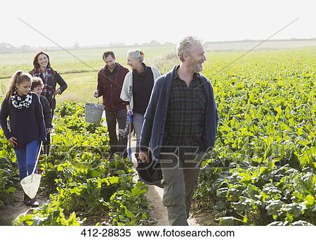 Stock Photography - Multi-generation family walking in sunny vegetable garden. Fotosearch