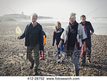 Stock Image - Multi-generation family walking on sunny beach. Fotosearch