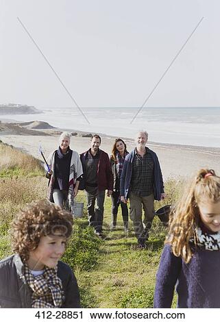 Stock Image - Multi-generation family walking on sunny grass beach path. Fotosearch