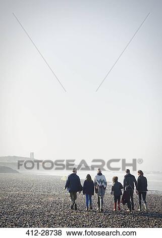 Multi-generation family walking on sunny beach in a row View Large Photo Image Stock Photo - Multi-generation family walking on sunny beach in a row. Fotosearch