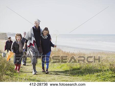 Stock Photograph - Multi-generation family walking on grassy beach path. Fotosearch