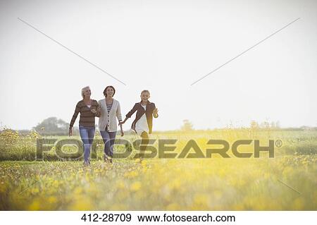 Stock Photo - Multi-generation women walking in sunny meadow. Fotosearch